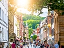 Belebte Strasse mit historischen Gebäuden im Sonnenschein.