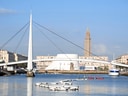 Moderne Brücke und Gebäude am Wasser vor einem Turm.