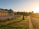 Sonnenuntergang über Schloss Sanssouci mit Garten im Vordergrund.