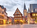 Historische Fachwerkhäuser auf einem Kopfsteinpflasterplatz bei Abenddämmerung.