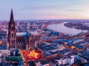 Panoramablick auf eine Stadt mit grosser Kirche und Fluss bei Sonnenuntergang.