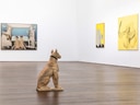 Kunstausstellungsraum mit Gemälden an der Wand und einer Hundeskulptur im Vordergrund.
