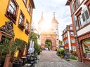 Pflasterstrasse mit bunten Gebäuden und historischem Tor.