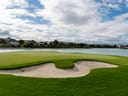 Golfplatz mit Sandbunker, Grün und See im Hintergrund.