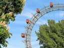 Riesenrad vor blauem Himmel und Bäumen.