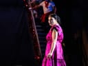 Frau in pinkfarbenem Kleid auf einer Bühne.