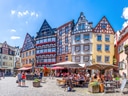 Malebener Platz mit Fachwerkhäusern und Strassencafés bei Sonnenschein.