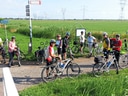 Gruppe von Radfahrern auf einem ländlichen Weg, umgeben von Feldern.