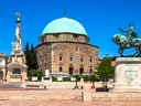 Historisches Gebäude mit Kuppel und Reiterstatue auf Platz.