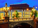 Historische Brücke bei Nacht mit beleuchtetem Opernhaus im Hintergrund.