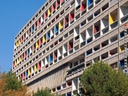 Mehrstöckiges Gebäude mit bunten Balkonen vor blauem Himmel.