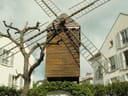 Historische Windmühle zwischen Gebäuden mit Restaurant im Erdgeschoss.