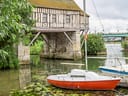 Boot vor einem historischen Gebäude an einem Fluss mit Seerosen.