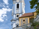 Barockkirchturm mit blauem Himmel und Wolken.