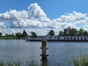 Grosses Schiff auf einem Fluss unter bewölktem Himmel.