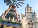 Weihnachtsmarkt mit Holzpyramide und Kirche im Hintergrund.