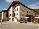 Altes Gebäude mit Holzelementen, Aussenterrasse mit Sonnenschirmen.