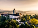 Luftaufnahme einer Burg in ländlicher Landschaft bei Sonnenaufgang.