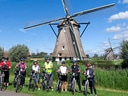 Gruppe von Radfahrern vor einer Windmühle.