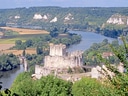 Landschaft mit Fluss, Burg und Hügeln im Hintergrund.