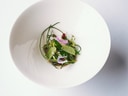 Weisse Schüssel mit grünem Salat und essbaren Blüten.