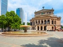Opernhaus mit Brunnen und Hochhäusern im Hintergrund bei Tag.