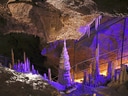 Stalagmiten und Stalaktiten in einer beleuchteten Höhle.