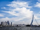 Erasmusbrücke über Fluss mit Stadt im Hintergrund.
