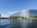 Moderne Glasgebäude am Flussufer bei klarem Himmel.
