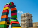 Bunte Containerbögen vor modernen Gebäuden unter blauem Himmel.