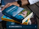 Person mit Büchern auf einem Tisch.