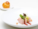 Drei Würfel Pastete mit roter Sauce, garniert mit Grün, auf weissem Teller.