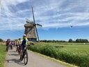 Radfahrer auf einem Weg neben einer Windmühle.