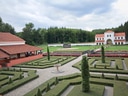Rekonstruktion eines römischen Landguts mit gepflegten Hecken und Gebäuden, umgeben von Wald.