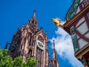 Rotes Rathaus und Kirchturm bei blauem Himmel.