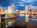 Stadtansicht bei Nacht mit Fluss und modernen Gebäuden.