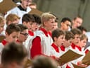 Gruppe von Jungen in weissen und roten Gewändern singt in einem Chor.