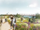Menschen spazieren auf einem Weg durch einen blühenden Garten mit Brücke im Hintergrund.