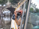 Person mit Kamera lehnt sich aus Bootsfenster.