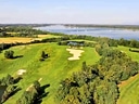 Luftaufnahme eines Golfplatzes neben einem Fluss.