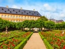 Barockgarten mit bunten Blumen und historischem Gebäude im Hintergrund.