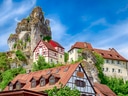 Traditionelle Fachwerkhäuser und Felsen unter blauem Himmel.