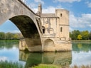 Alte Steinbrücke über einen Fluss mit blauem Himmel.