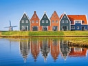 Traditionelle Häuser und Windmühle am Flussufer mit Spiegelung.