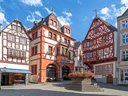 Historische Fachwerkhäuser mit Brunnen auf einem Platz.