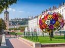 Platz mit Blumenskulptur und springenden Brunnen vor Altstadt.