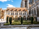 Garten vor alter Kathedrale mit Bäumen und gotischen Bögen.