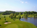 Luftaufnahme eines Golfplatzes mit Wasserhindernis und Bäumen.