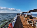 Menschen auf einem Schiffdeck mit Blick auf das Meer.
