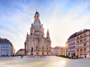 Platz mit historischer Kirche und umliegenden Gebäuden bei Sonnenuntergang.
